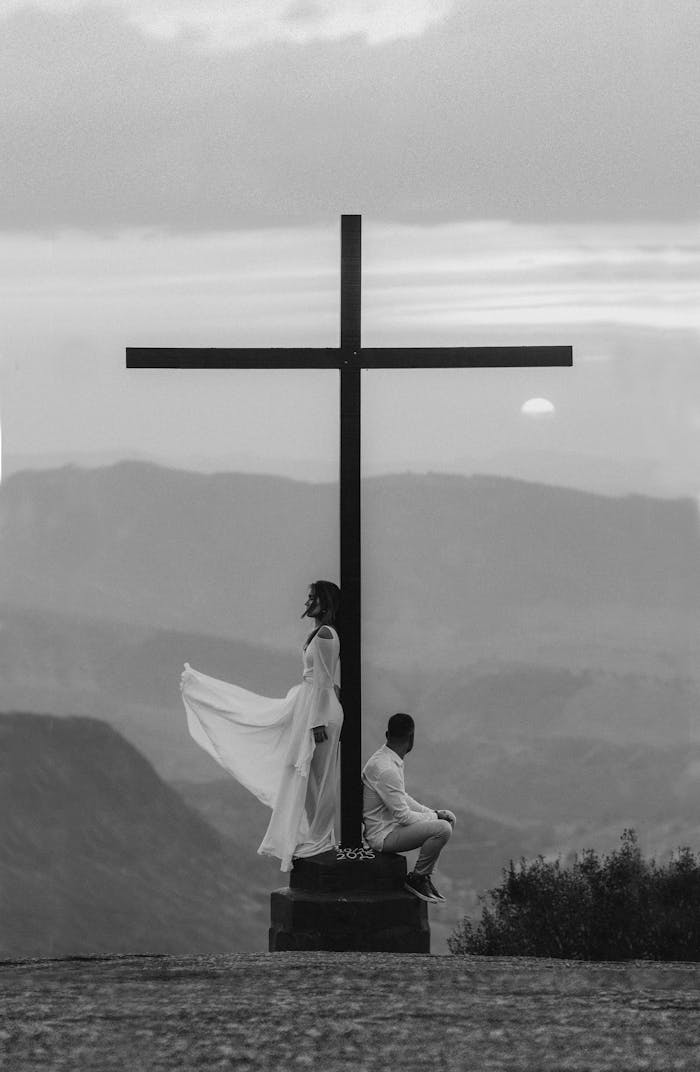 about-us A serene moment of spiritual reflection by a cross at sunset with a dramatic sky in the background.